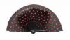 Black fan in wood painted with red polka dots on both sides.